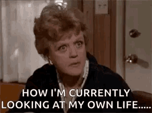 a woman is sitting at a table with a door in the background and looking at her own life .