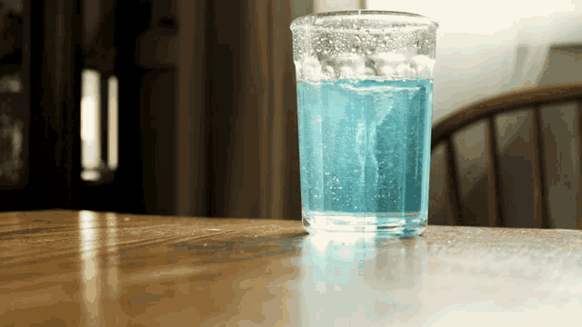 a glass of blue liquid is on a table