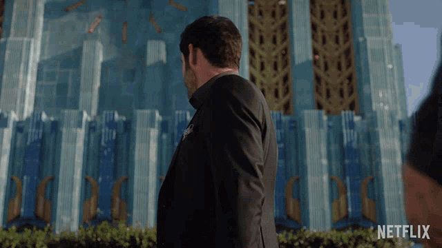 a man in a suit stands in front of a building that says netflix on the bottom