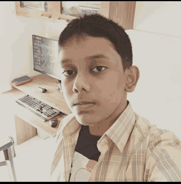 a young boy takes a selfie in front of a computer