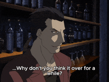a glass of whiskey with ice sits on a bar with a man in the background