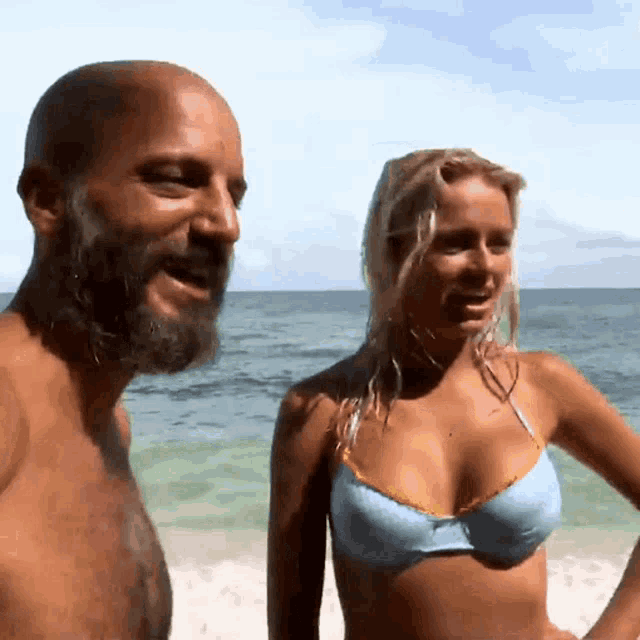 a man with a beard and a woman in a bikini are on a beach