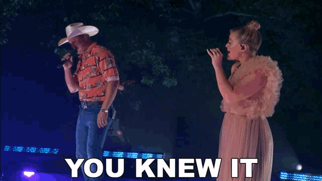 a man in a cowboy hat and a woman in a pink dress singing into microphones with the words you knew it behind them