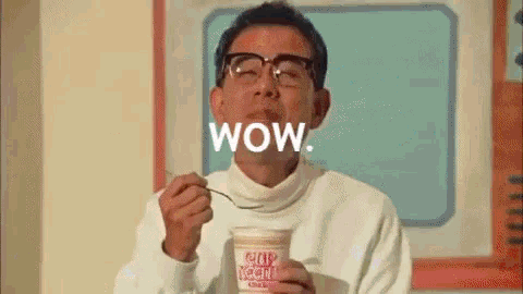 a man is eating a cup of noodles with a spoon and the word wow is written above him .