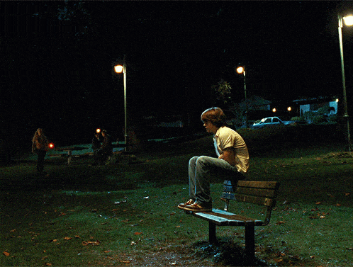a man sits on a bench in a dark park at night
