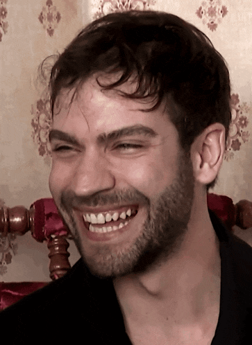 a close up of a man 's face with a beard smiling