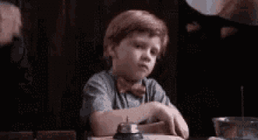 a young boy is sitting at a table with a bell on it .