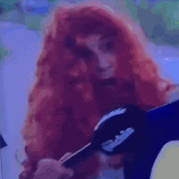 a woman with red hair is holding a comb and looking at the camera .