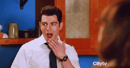 a man in a white shirt and tie is covering his mouth with his hand while looking at a woman in a kitchen on citytv