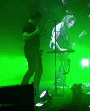 a man in a black shirt is playing a keyboard in front of a green background