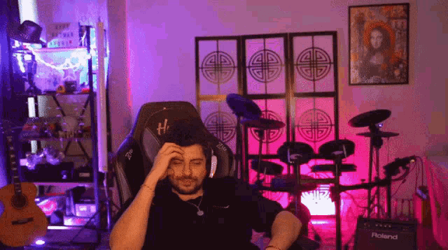 a man sitting in a chair in front of a roland amplifier