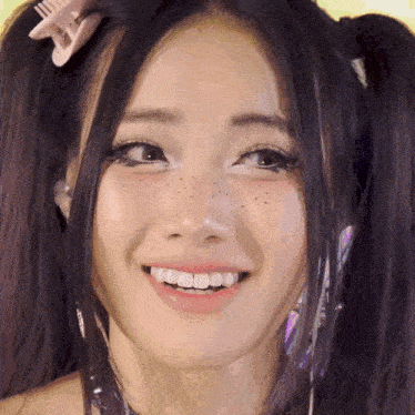 a close up of a woman with pigtails and freckles smiling