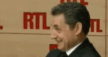 a man in a suit is smiling in front of a sign that says rtl