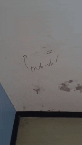 a person is giving the middle finger to someone who has written huh-uh on the wall
