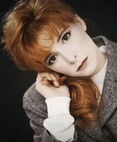 a woman with red hair is wearing a gray jacket
