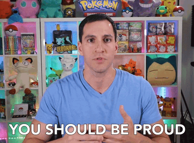 a man in a blue shirt says you should be proud in front of a pokemon collection