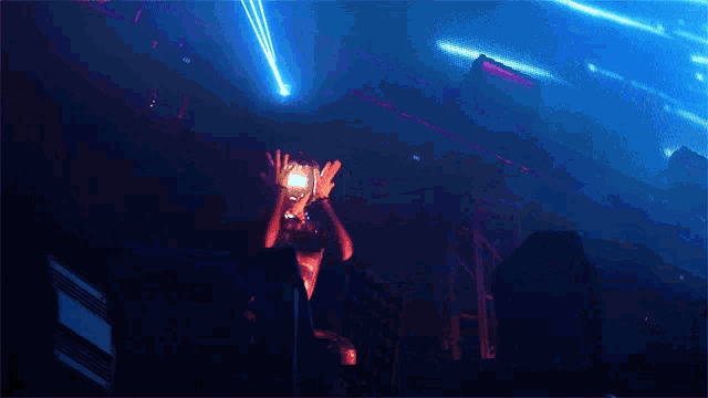 a man in a glow in the dark outfit stands in front of a stage with blue lights