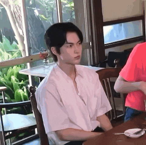 a man in a white shirt is sitting at a table with a spoon in his hand .