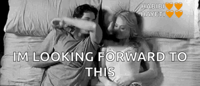 a black and white photo of a man and a woman laying in bed .
