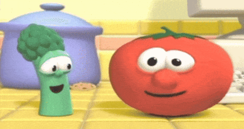 a tomato and broccoli are standing next to each other on a counter .