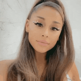 ariana grande is wearing a ponytail and rhinestones in her eyelashes .