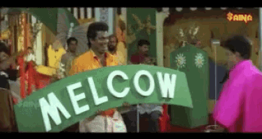 a man in a pink shirt holds a green sign that says melcow