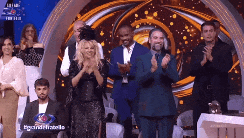 a group of people standing on a stage with the words grande fratello written on the bottom