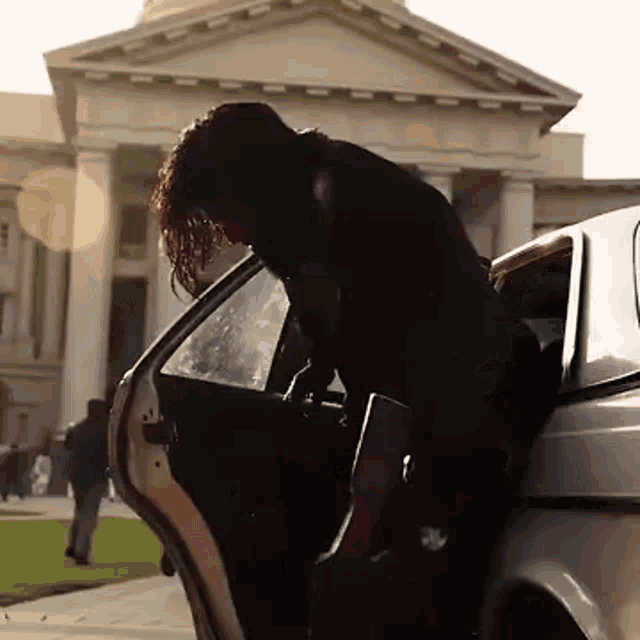 a man getting out of a car in front of a building