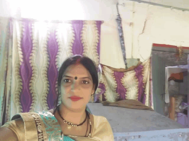 a woman taking a selfie with a purple and white curtain in the background