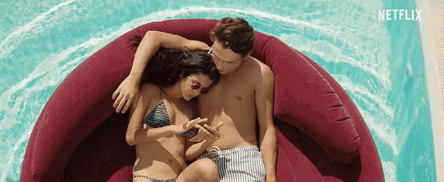 a man and a woman are laying on a red couch in a pool with netflix written on the bottom