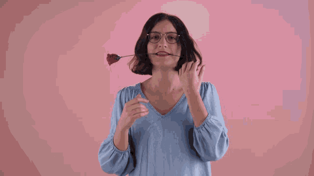 a woman with glasses holds a rose in her mouth