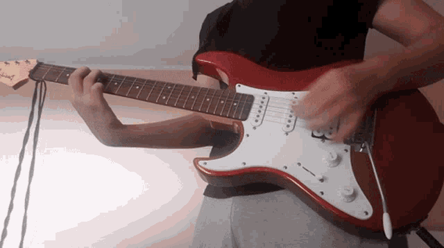 a person is playing a red guitar with the brand name jackson on it