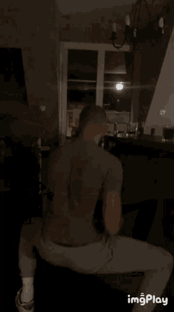 a man squatting down in a dark room with the words imgplay visible