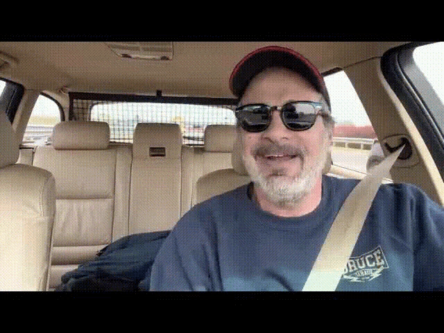 a man wearing sunglasses is sitting in the back seat of a car wearing a shirt that says buce