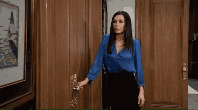 a woman in a blue shirt stands in a doorway