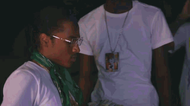 a man wearing a bandana around his neck has a necklace with a pendant that says ' king '