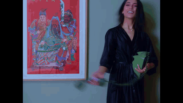 a woman in a black robe is holding a green telephone in front of a framed picture