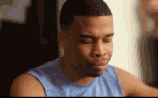 a man wearing a blue tank top is making a funny face