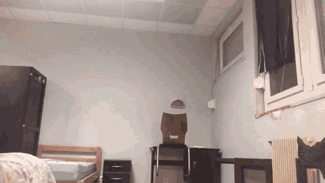 a room with a bed a desk and a window with a box on the wall