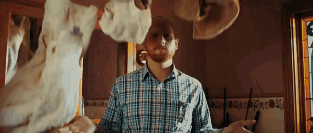 a man in a plaid shirt is standing in front of a pile of clothes .