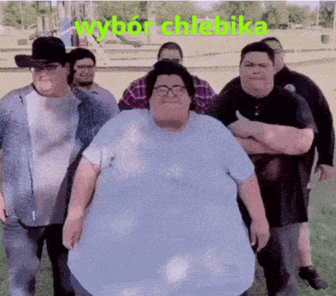 a group of fat men are standing in a park with wybor chlebika written in green letters