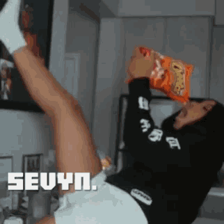 a woman laying on the floor eating a bag of cheetos chips
