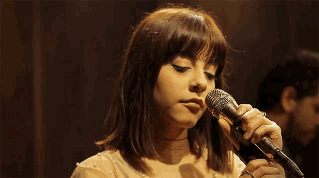 a woman singing into a microphone while a man stands behind her