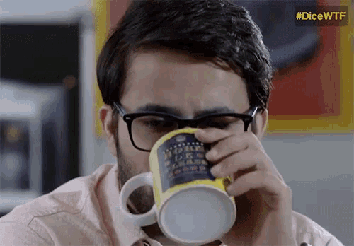 a man wearing glasses is drinking from a mug that says " i 'm a geek " on it