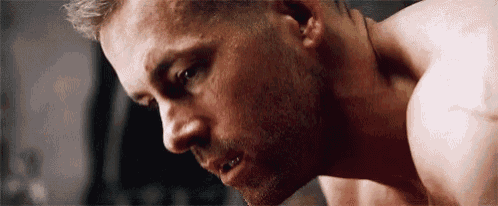 a close up of a man 's face with a beard and no shirt on .