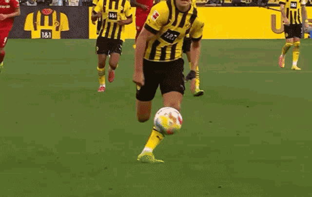 two soccer players are playing a game on a field . one of the players is kneeling down .