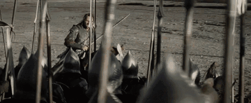 a man is standing in front of a row of spears .