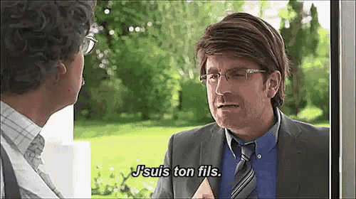 a man in a suit and tie is talking to another man in a blue shirt ..