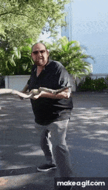 a man in a black shirt is holding a large snake in his hands
