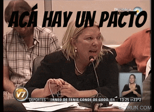 a woman speaking into a microphone with the words " aca hay un pacto " behind her